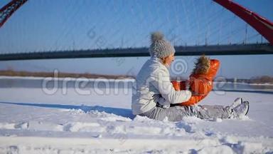 女孩在冬天阳光明媚的时候和宝宝玩。 双手握着。 河面斜拉桥